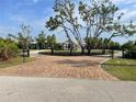 Stunning home featuring a circular brick driveway, lush trees, and an iron gate entrance at 27320 Egret Pl, Punta Gorda, FL 33983