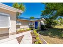 Inviting front entrance featuring a blue door, decorative shutters, a quaint walkway, and lush tropical landscaping at 28482 Coco Palm Dr, Punta Gorda, FL 33982