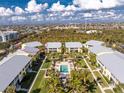 Aerial view of condo community featuring a swimming pool and lush landscaping against a blue sky backdrop at 2000 Bal Harbor Blvd # 1-111, Punta Gorda, FL 33950