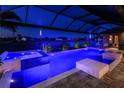 Relaxing private pool and spa area at night, featuring ambient lighting, screened enclosure, and outdoor furniture at 17122 Barcrest Ln, Punta Gorda, FL 33955
