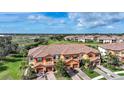 A stunning aerial view of a townhome community, featuring a tile roof, landscaping, and lake views at 20272 Lagente, Venice, FL 34293