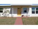 Inviting front entrance with a vibrant yellow door and a cozy bench, perfect for enjoying the outdoors at 21456 Holdern Ave, Port Charlotte, FL 33952