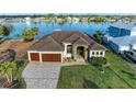 Stunning waterfront home featuring a two-car garage and a paved driveway surrounded by lush landscaping at 349 Springview Nw Cir, Port Charlotte, FL 33948