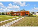 Single story home with a lush lawn and a vibrant orange facade at 520 Sharon Cir, Port Charlotte, FL 33952