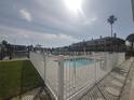 Community pool offers a refreshing escape, surrounded by a secure fence and palm trees for privacy at 11723 1St E St, Treasure Island, FL 33706