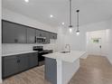 Modern kitchen with gray cabinets, stainless steel appliances, an island with quartz countertop, and wood-style tile flooring at 1790 New London St, North Port, FL 34288