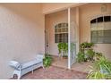 Covered front porch features a brick floor, bench seating, decorative gate, and plenty of plants at 2175 Lynx Run, North Port, FL 34288