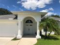 Inviting white home entrance features a beautiful arched entryway, double doors, and a well-manicured lawn at 223 Valdiva St, Punta Gorda, FL 33983