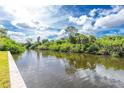 Scenic waterfront view showcasing lush greenery, tranquil waters, and clear sky with scattered clouds at 626 Lomond Dr, Port Charlotte, FL 33953