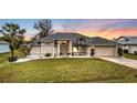 Inviting home exterior with lush lawn, well-kept landscaping, and lovely sunset at 73 Santarem Cir, Punta Gorda, FL 33983