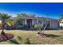 Inviting single-story home featuring a manicured lawn, mature palms, and a welcoming covered entrance at 1675 Blue Lake Cir, Punta Gorda, FL 33983