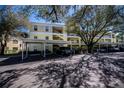 View of condo parking area featuring covered parking, beautiful trees, and well maintained landscaping at 19335 Water Oak Dr # 202, Port Charlotte, FL 33948