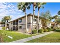 Exterior view of condo with mature palms, well-maintained lawn, and a charming screened-in porch at 19505 Quesada Ave # Ee204, Port Charlotte, FL 33948