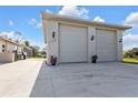 Spacious detached two-car garage with ample parking space, complemented by potted flowers and exterior lighting at 3080 Belleville Ter, North Port, FL 34286