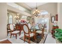 Elegant dining room features a glass table, chandelier, high ceilings, and ample natural light from a large window at 26373 Madagascar, Punta Gorda, FL 33983