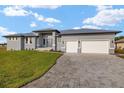 Gray home with a paved driveway, a manicured front lawn, and a three-car garage at 7363 N Moss Rose, Punta Gorda, FL 33955