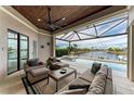 Screened-in outdoor living space featuring comfortable seating overlooking a pool and canal at 1492 Aqui Esta Dr, Punta Gorda, FL 33950