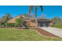 A front exterior of a beautiful tan home, with palm trees, a manicured lawn, and a clean driveway at 1525 Hinton St, Port Charlotte, FL 33952