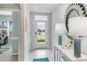 Bright foyer with white tiled floors, modern console table, and decorative mirror reflecting the natural light at 16395 Larocha Dr, Punta Gorda, FL 33955
