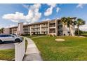 Condo building with a sidewalk, palm trees, and well-maintained green lawn at 175 Kings Hwy # 538, Punta Gorda, FL 33983