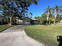 Well-manicured lawn with mature trees enhances the curb appeal of this home with an attached garage at 20262 Hamilton Ave, Port Charlotte, FL 33952