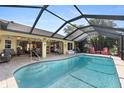 Screened-in pool with blue water, surrounded by patio space, lounge seating, and tropical foliage at 1225 Neapolitan Rd, Punta Gorda, FL 33983