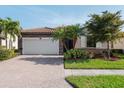 Charming home showcasing a stone accent facade, paver driveway, and lush tropical landscaping at 12285 Canavese Ln, Venice, FL 34293