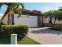 Home exterior features a two-car garage, brick driveway, and well-maintained landscaping at 12285 Canavese Ln, Venice, FL 34293