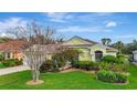 Single-story yellow home featuring a beautiful tile roof, front lawn with professional landscaping, and inviting curb appeal at 1616 Palmetto Palm Way, North Port, FL 34288