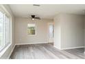 Bright living room with gray wood-look floors, neutral walls, a ceiling fan, and natural light at 3213 Normandy Dr, Port Charlotte, FL 33952