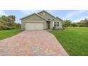 Charming single-story home with a brick driveway, manicured lawn, and attached garage at 616 Posadas Cir, Punta Gorda, FL 33983