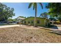 Green home with well kept lawn and minimal landscaping with trees and plants at 8035 Hillman Ave, Punta Gorda, FL 33982