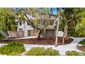Exterior angle showcasing the property's architecture surrounded by mature trees and a white rock garden at 5239 Siesta Cove Dr, Sarasota, FL 34242
