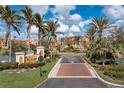 Community entrance with lush landscaping, mature palms, and red brick drive in the Vivante community at 85 Vivante Blvd # 8542, Punta Gorda, FL 33950