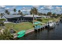 Waterfront home featuring screened-in pool area, dock, boat lift, and lush green lawn at 129 Barre Nw Dr, Port Charlotte, FL 33952