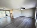 Open-concept living room showcases gray wood-look flooring, a ceiling fan, and adjacent kitchen and patio access at 2507 Linton Ln, Port Charlotte, FL 33952