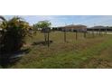 Expansive backyard with a partial fence, featuring scattered vegetation and sunlight, offers a serene outdoor setting at 30035 Alder Rd, Punta Gorda, FL 33982