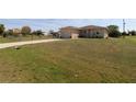 Sprawling lawn leads to a single-story home with an attached garage on a sunny day, promising ample outdoor space at 30035 Alder Rd, Punta Gorda, FL 33982