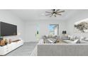 Bright living room featuring gray sofas, modern decor, a ceiling fan, and an art piece on the wall at 4818 Kiska Rd, North Port, FL 34288