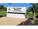 The Burnt Store Meadows community entrance sign is surrounded by lush green landscaping and tropical palm trees at 7534 Carissa, Punta Gorda, FL 33955