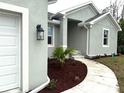 Close-up view of the home's entrance showing the front door, walkway, and neatly arranged garden beds at 9590 Little Rock St, Port Charlotte, FL 33981