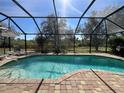 Inviting screened-in pool area with brick pavers, lounge chairs, and a view of the natural surroundings at 10052 Winding River Rd, Punta Gorda, FL 33950