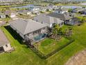 Aerial view of a backyard with a screened-in pool and a well-maintained lawn surrounded by a black fence at 15809 Appalachian Dr, Punta Gorda, FL 33982