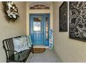 Inviting front porch features a vibrant blue door, welcome sign, and comfortable bench at 1944 Boddington Trl, Port Charlotte, FL 33980