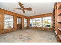 Cozy living room with wood-paneled walls, a ceiling fan, and multiple windows offering plenty of natural light at 231 Winson Ave, Englewood, FL 34223