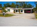Single-story home with well-maintained lawn, mature trees, and covered carport for parking at 2521 Clipper Ship Way, Sarasota, FL 34231