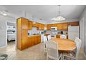 Eat-in kitchen features wood cabinets, white appliances, tile floor and eat-in wooden table at 380 Base E Ave # 202, Venice, FL 34285