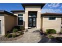 Inviting home entrance showcasing a tiled walkway, well-manicured landscaping, and a modern glass door at 556 Monaco Dr, Punta Gorda, FL 33950
