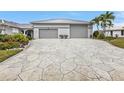 View of the home's garage with a uniquely patterned concrete driveway and lush landscaping at 112 Great Isaac Ct, Punta Gorda, FL 33950