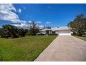 Charming one-story home features a long driveway and a spacious front yard with lush green grass at 1169 Presque Isle Dr, Port Charlotte, FL 33952